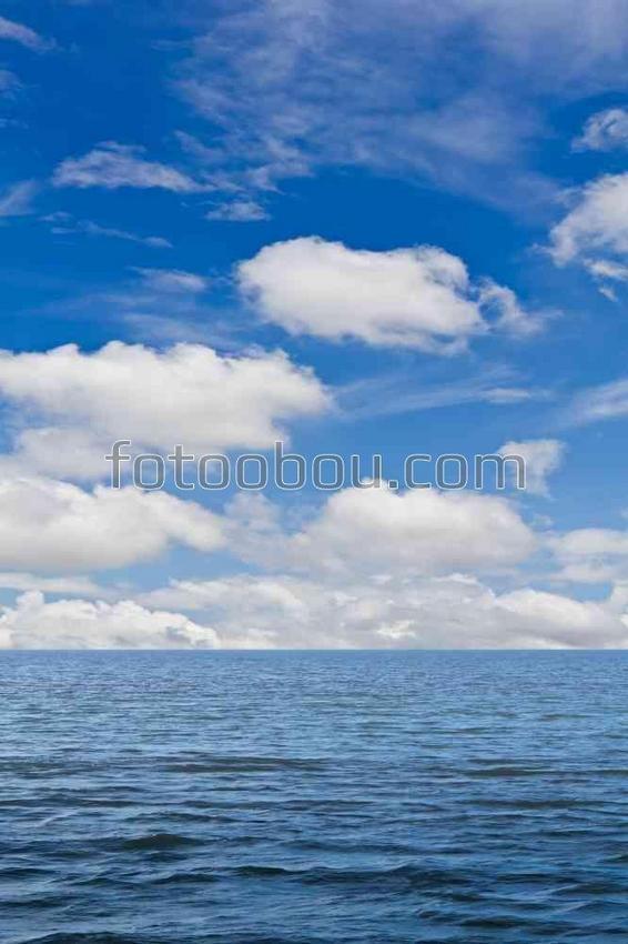 Белые облака в голубом небе над синим морем