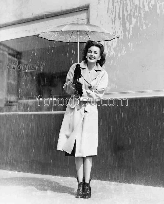 Девушка под зонтиком прячется от дождя