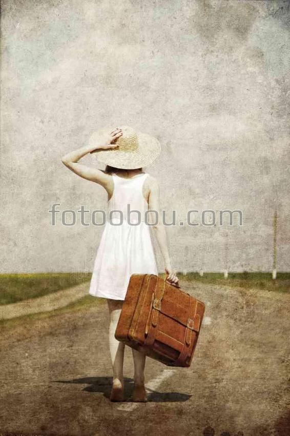 Девушка с чемоданом стоит на дороге